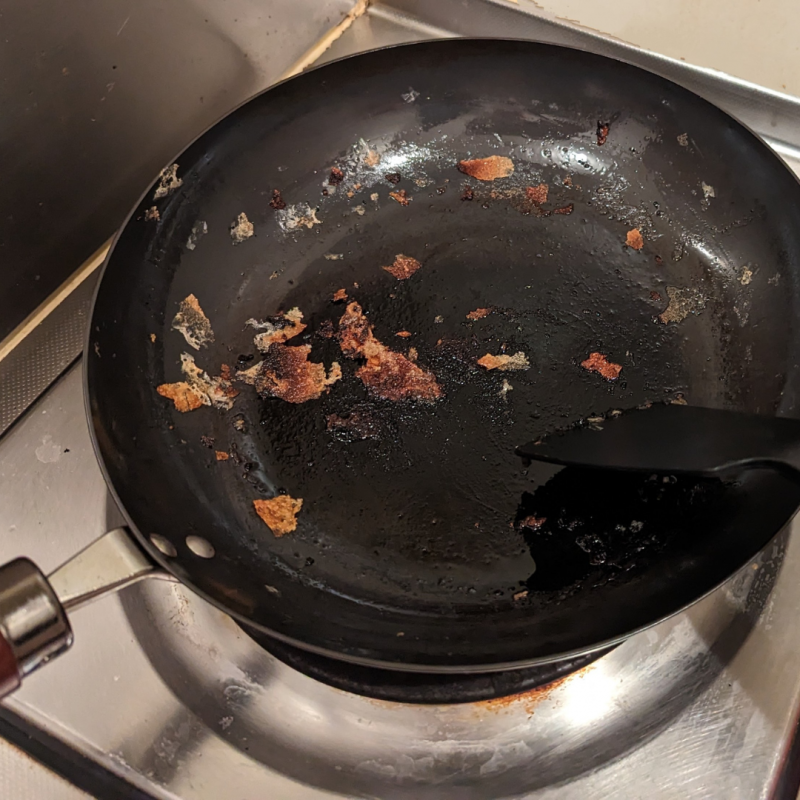 キッチンのひとくちコンロに餃子を焼き終わったリバーライト極JAPANフライパンが置かれている。

フライパンには、餃子のカリカリに焼けた羽の部分がいくつか残っている。