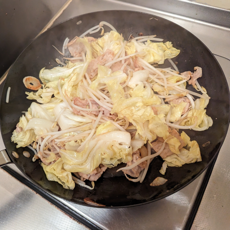 キッチンのひとくちコンロにリバーライト極JAPANフライパンをかけ、野菜炒めを作っている画像。

キャベツ、もやし、豚肉、にんにくを使った野菜炒め。フライパンからはうっすら熱気を示す湯気が上がっているのが分かる画像。