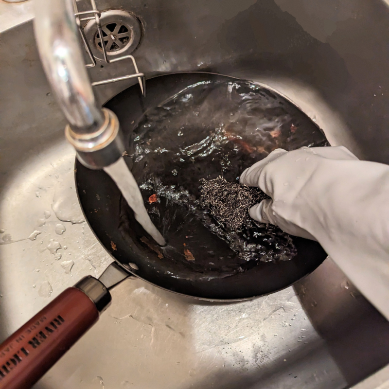 シンクで使い終わったリバーライト極JAPANフライパンを洗っている画像。

水道から水を流しながら金タワシでフライパンを洗っている。